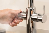 AEG Heißwassersystem HOT 5: Über den linksseitiges Griff mit rotem Sicherheits-knopf, der zum Schutz vor Verbrühung im Drück-Dreh-Verfahren betätigt wird, erfolgt die Heißwasserentnahme. Rechts lässt sich mit dem Einhebelmischer kaltes und warmes Wasser zapfen. Bild: AEG Haustechnik