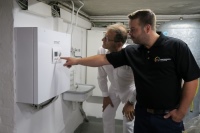 Heizungsfachmann Marcel Medding erläutert dem Betreiber die intuitive Bedienung: Zwei Taster und ein Handrad genügen, um die Wärmepumpe zu regeln.