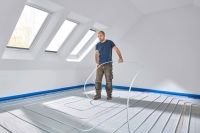 Das Klettsystem lässt sich ohne weiteres Zubehör auch von nur einer Person verlegen. Das Rohr wird einfach per Fußabdruck auf die Dämmplatte fixiert.<br />Bilder: Uponor