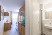 Die Nassauische Heimstätte, die die Apartments im Cubus130 in Frankfurt möbliert vermietet, bietet zwei Ausstattungslinien an: Studioline in schwarz-weiß sowie Greenwood in warmen Holztönen. Die Badezimmer mit Sanitärausstattung von Geberit strahlen immer in puristisch-modernem Weiß.