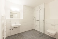 Die barrierefreien Bäder fallen etwas geräumiger aus und besitzen eine bodenebene Dusche mit einer CleanLine20 Duschrinne von Geberit. Die Sanitärkeramik aus der Serie Renova Plan stammt ebenfalls von Geberit. Ein Unterputzsiphon am Waschtisch erhöht die Bewegungsfreiheit.