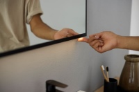 Die Beleuchtung des Geberit Option Plus Square Spiegels lässt sich entweder mittels Touch-Sensor am Spiegel oder über den Lichtschalter des Badezimmers bedienen. Hier im Bild das neue Modell mit schwarz mattem Rahmen.