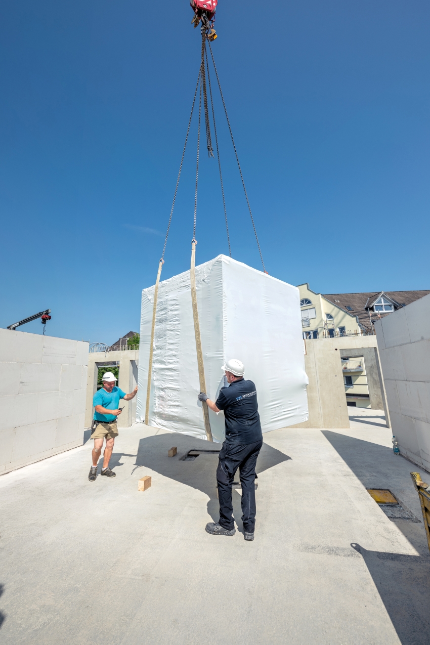 Monteure nehmen das vorgefertigte Badmodul vom Kran...