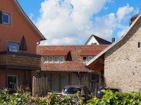 Der Dreiseithof von der Straße aus gesehen. Links im Bild das alte Haupthaus, in dem ebenso Ferienwohnungen wie in dem mittig und rechts im Bild zu sehenden L-förmigen ehemaligen Stall- und Werkstattgebäude sind.