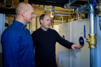 Daniel Kuoppala (rechts), Inhaber der ausführenden Installationsfirma, und Johan Väisänen, Eigentümer der Arctic River Lodge, erläutern die Funktionsweise der Erdwärmepumpen von Bosch. 