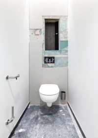 Nach der Vorwand-Installation erfolgen die Beplankung und Befliesung. Anschließend werden die Sanitärprodukte angebracht – hier zu sehen das spülrandlose WC, der Anschluss für die Betätigungsplatte sowie die Halterungen für Toilettenpapier und WC-Bürste. <br />Bilder: Geberit<br />