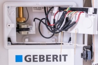 Stark vernetzt: Im Inneren der Geberit Hygienespülung zeigen sich die Steuerungstechnik sowie Rückstausensoren. Sollte es im Störfall zum Anstieg des Wasserpegels kommen, wird die Spülung automatisch gestoppt und ein Fehler ausgegeben. 