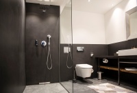 Einige Zimmer haben klassisch gestaltete Bäder mit bodenebener Dusche, Dusch-WC und Waschplatz. Durch die anthrazitfarbenen, teilweise raumhohen Fliesen sowie den marmorierten Boden erhalten sie einen edlen Look.