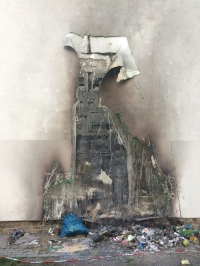 Mülltonnenbrand an einer gedämmten Wand. Gut zu sehen im oberen Bereich: Die nicht verbrannte Polystyrol-Dämmung dank Flammschutzmittel. <br />Bild: fy