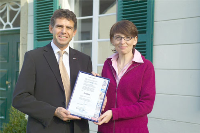 Horst Becker (Gründer und Inhaber von Isotec) und Sandra Haberth (stellv. Leiterin des Schumannhauses) bei der Übergabe des Isotec-Zertifikats für 40 Jahre trockene Wände. <small>(Foto: Isotec GmbH)</small>