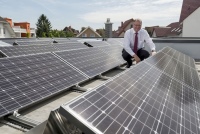 Heinz Jörg Göbert auf dem Flachdach seines Bungalows inmitten von 74 Photovoltaikmodulen.<br />Bilder: Panasonic