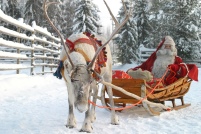 Weihnachtsmann im Schlitten mit Rentier.