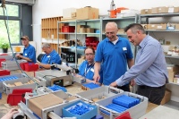 Die Beschäftigten der Caritas Werkstätten sind für das Magazinieren der Schütz Heizrohrhalter zuständig und wirken dadurch bei der Fertigung von Flächenheizungen mit. Die Heizrohrhalter werden dafür aufgereiht und anschließend miteinander verschweißt. Gruppenleiter Robert Krämer (Caritas Werkstätten) und Thomas Meyer (Einkauf SCHÜTZ) begutachten die fertige Arbeit.