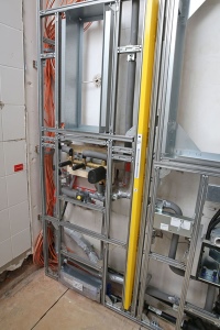 Links an den Waschplatz schließt sich der Duschbereich an. Im Installationssystem befinden sich bereits der Montagerahmen für die Geberit ONE Nischenablagebox sowie die Elemente für die rahmenlose Duschtrennwand (mit gelber Abdeckung) und den Geberit Wandablauf.