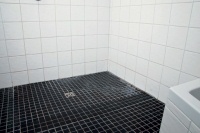 Durchgefliester Duschbereich: Hohe Temperaturen sowie Nässe und Luftfeuchtigkeit begünstigen das Wachstum von verschiedenen Mikroorganismen wie Bakterien oder Schimmel im Bad.