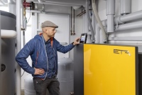 Planer Steffen Schwab am Display der neuen Holzpellets-Heizungsanlage.