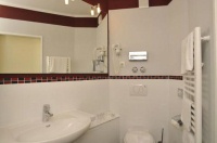 Als Kontrastfarbe an den Wänden wurde ein warmer Bordeaux-Ton eingesetzt. Dieser Farbton wurde auch bei einem weiteren Gestaltungselement eingesetzt: Ein umlaufendes Glas- / Steinmosaik in Bordeaux und Schwarz aus kleinen Rechtecken sorgt für einen warmen Kontrast zu den weißen Wandfliesen und der Sanitärkeramik.