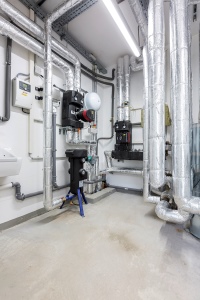 Knotenpunkt: Die Wärme aus der Luft-Wasser Wärmepumpe beziehungsweise dem dazwischen geschalteten Pufferspeicher VISTRON B und die Wärme aus den Dreizug-Öl-Brennwertkesseln wird hier gebündelt und verteilt. Über einen Wandregler ist die Luft-Wasser Wärmepumpe einstellbar. <br />Bilder: ELCO