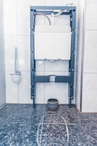 Der Grundrahmen des Sanitärmoduls wird in die montierten Befestigungsschrauben eingehängt und ausgerichtet.