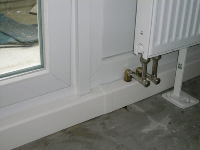 Fertiges Balkon- Fassadenelement mit gedämmtem Paneel hinter der Heizfläche, HZ- Heizkörperanschluss mit Ausgleichswinkelabsperrung und angepasstem Sockelleistenprofil.