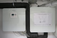 Die Hydrobox von BRÖTJE ist das hydraulische Bindeglied zwischen Wärmepumpe und Pufferspeicher (rechts). Links zu sehen ist die Powerbox, in der die NEO RWP Wärmepumpenregelung sitzt und alle elektrischen Komponenten zusammenlaufen.