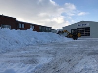 Der Schnee wird vor einer Lagerhalle geräumt.